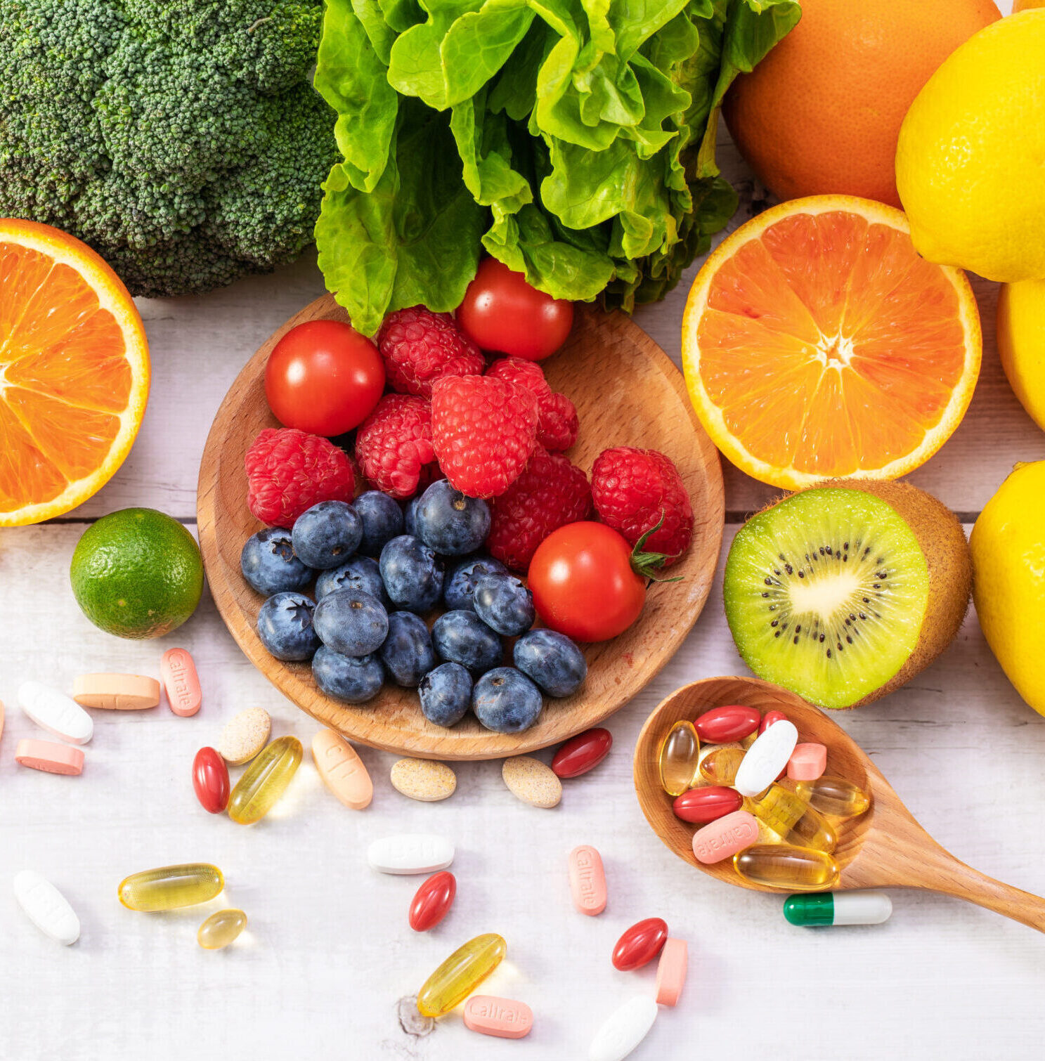 A top view of fresh fruits and vegetables with different medicine on a wooden spoon