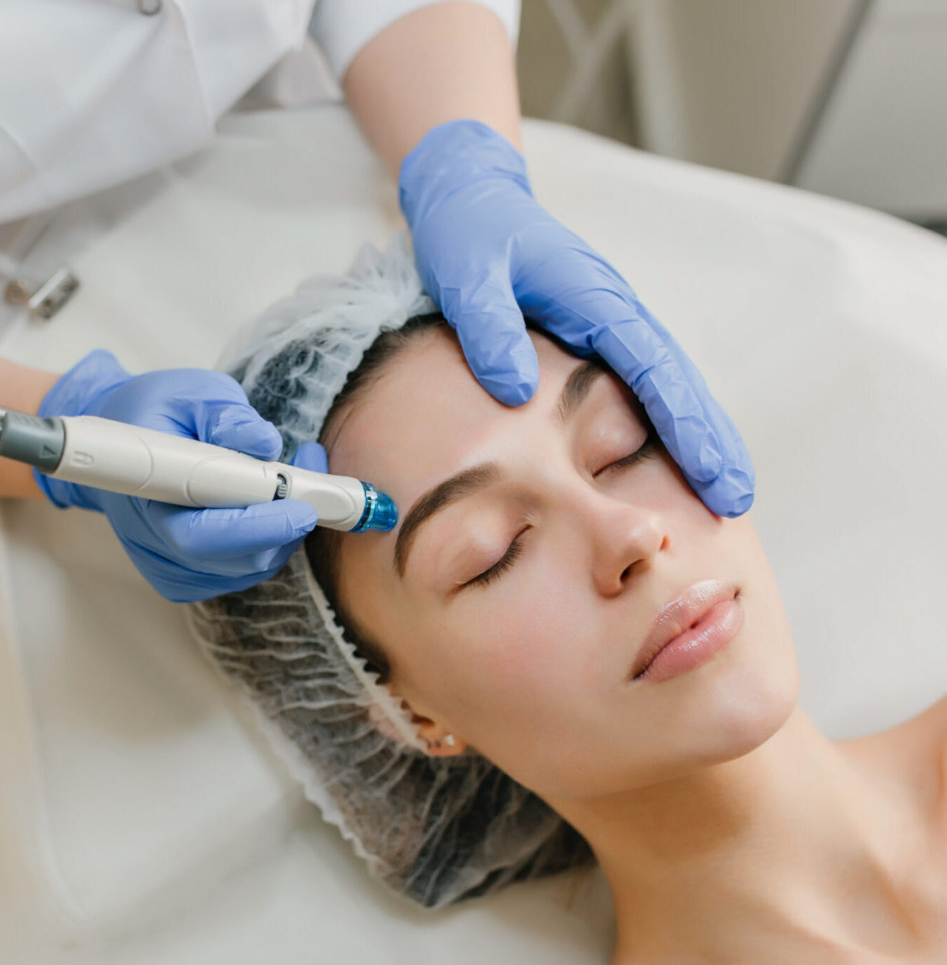 View from above rejuvenation of beautiful woman enjoying cosmetology procedures in beauty salon. Dermatology, hands in blue glows, healthcare, therapy, botox